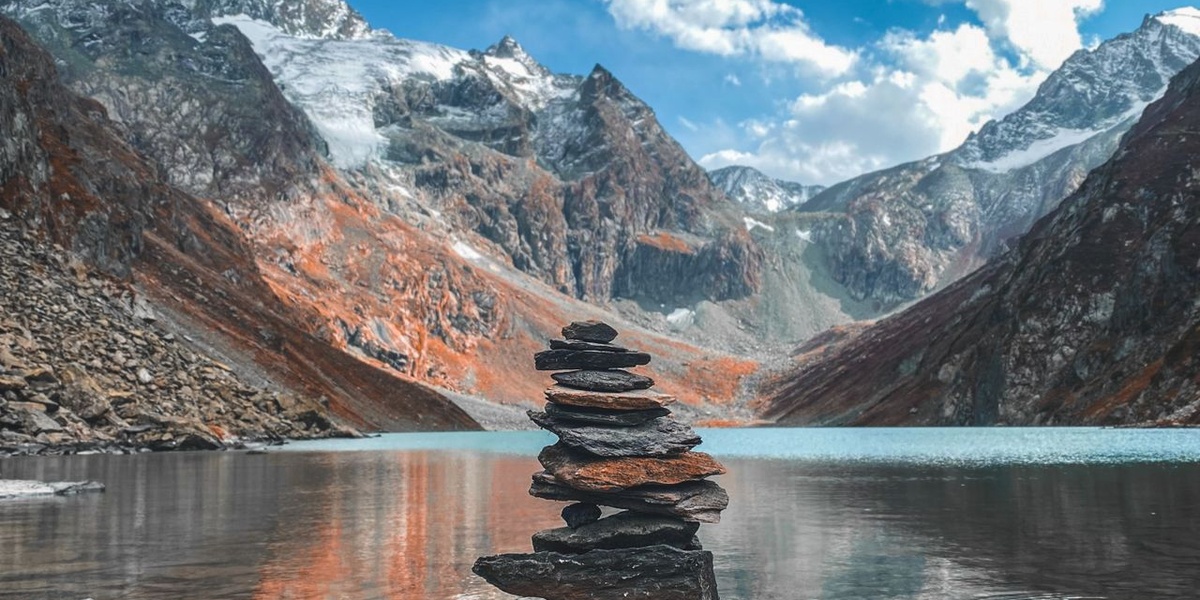 Stoic art of balance stacked zen stones in front of mountain alpine lake